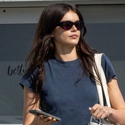 Kaia Gerber wearing a navy blue crop top and Paloma Wool's black skirt over pants while out in Los Angeles May 2024