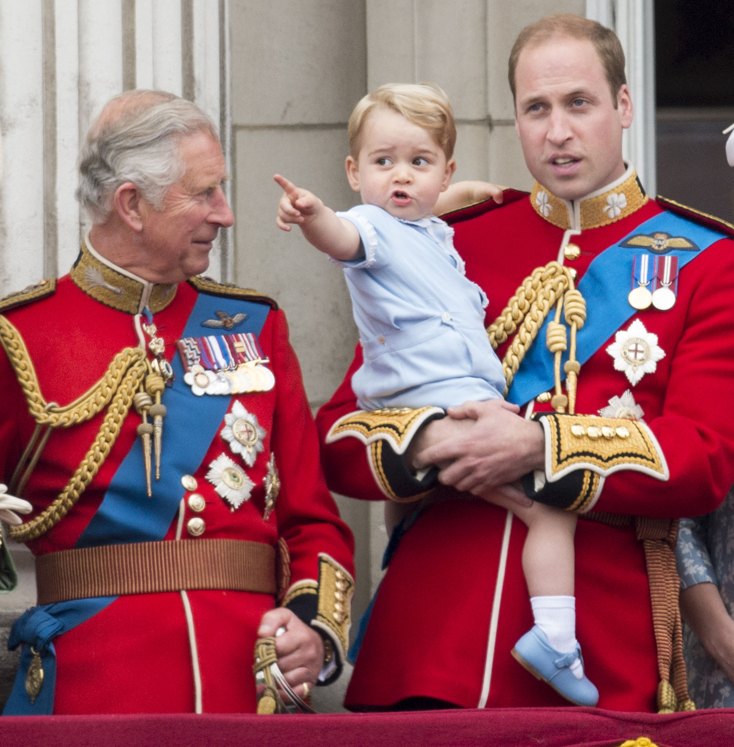 Prince William holding baby Prince George as King Charles smiles at him
