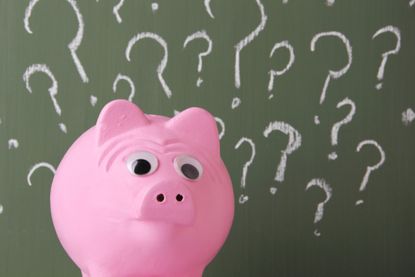 Piggy bank surrounded by wall full of question marks