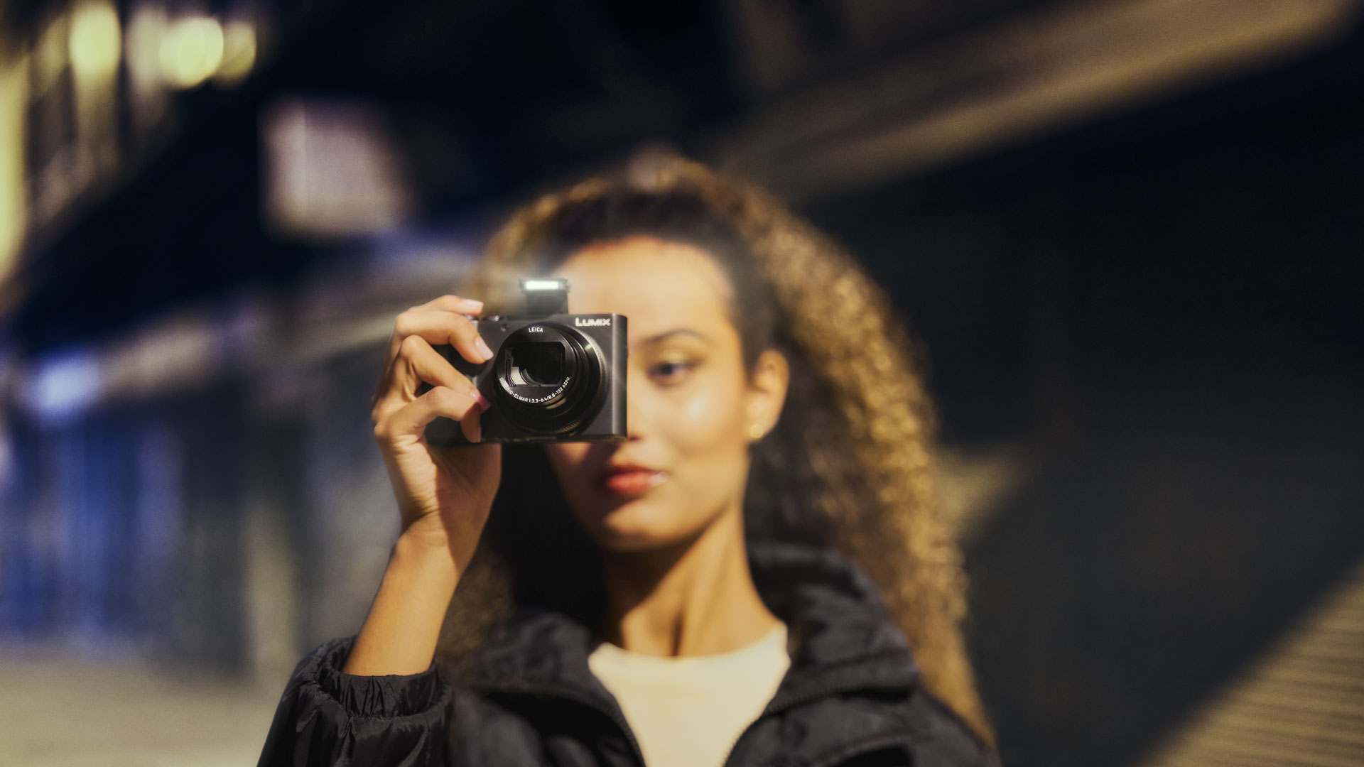 Panasonic Lumix TZ300 travel compact camera in a woman's hand, in an urban street at night