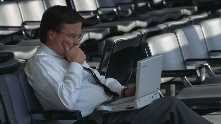 A businessman waiting at the US Air terminal in La Guardia Airport works on his laptop computer.