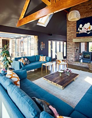 living room with sectional blue sofa roof beams doublesided fireplace with woodburner