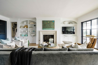 A neutral living room centred arund a marble fireplace and white cabinetry