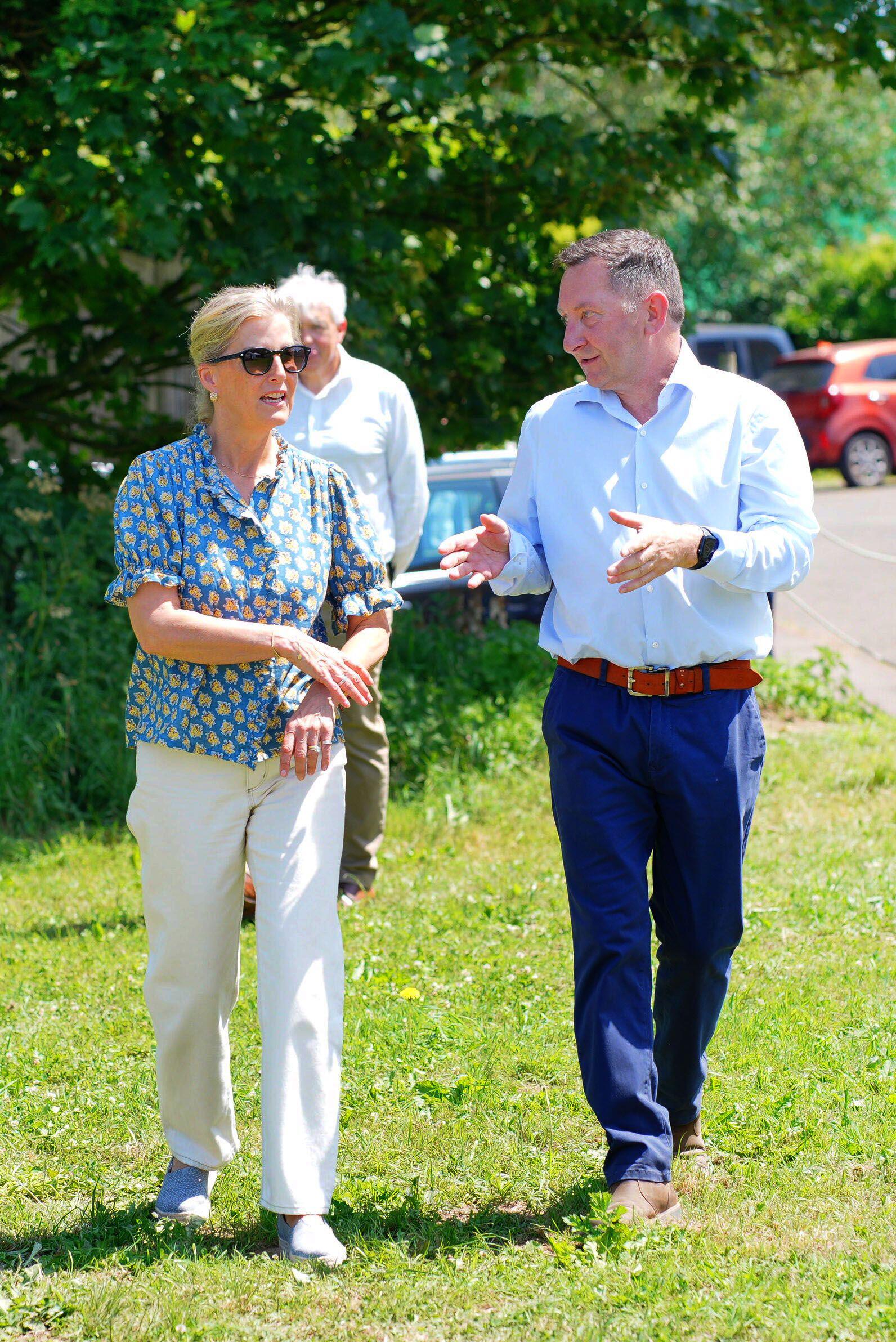 Duchess Sophie walking through grass talking to a man