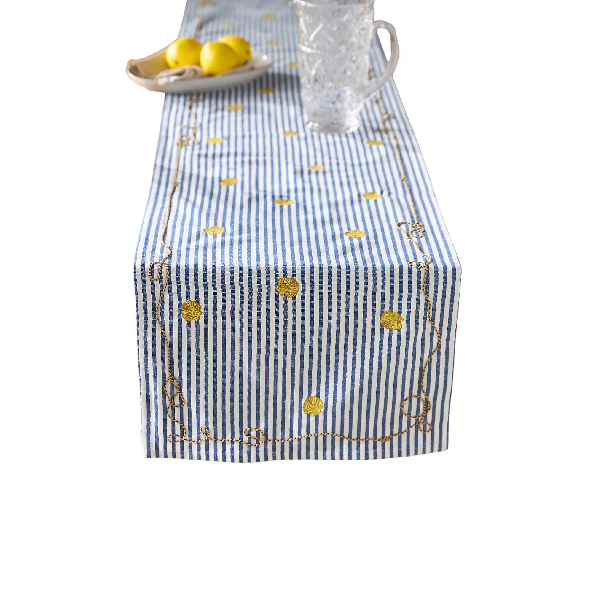 A table runner with white and blue stripes and a pitcher and lemons on top of it