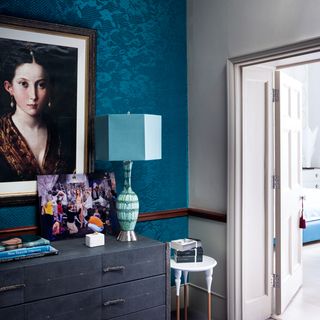 room with patterned blue wall and portrait frame