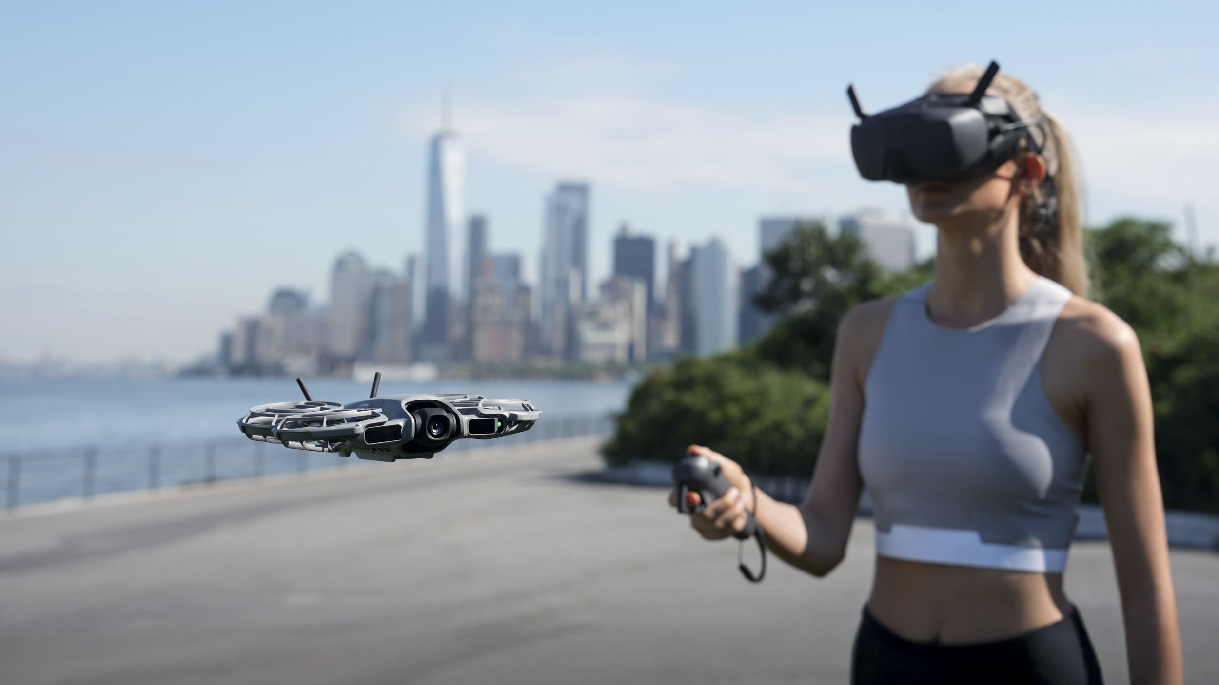 DJI Neo 2 selfie drone in flight with female in background wearing DJI goggles