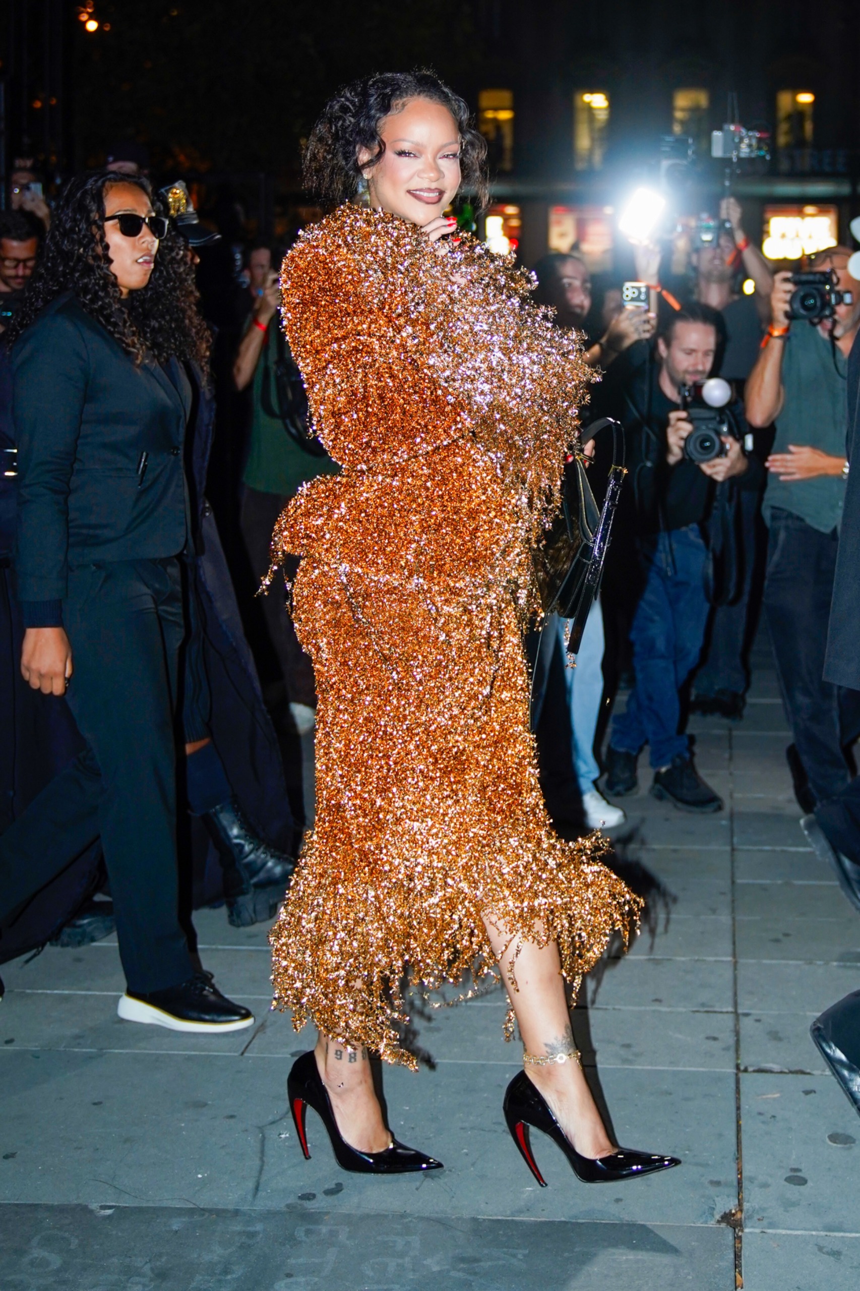Rihanna attends Mati&amp;egrave;res F&amp;eacute;cales's Spring/Summer 2027 show at Paris Fashion Week, wearing a glittery orange matching set and a peekaboo bra