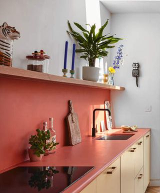 A modern kitchen with coral-red colored kitchen worktop and backsplash