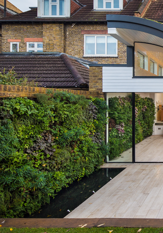 chic patio with pond, living wall and wood flooring continued from the kitchen inside