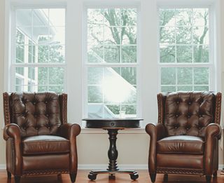 Empty Brown Leather Armchairs By Window At Home