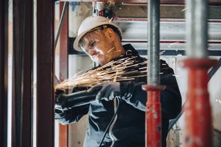 a close up of a builder drilling into a wall and sparks flying.