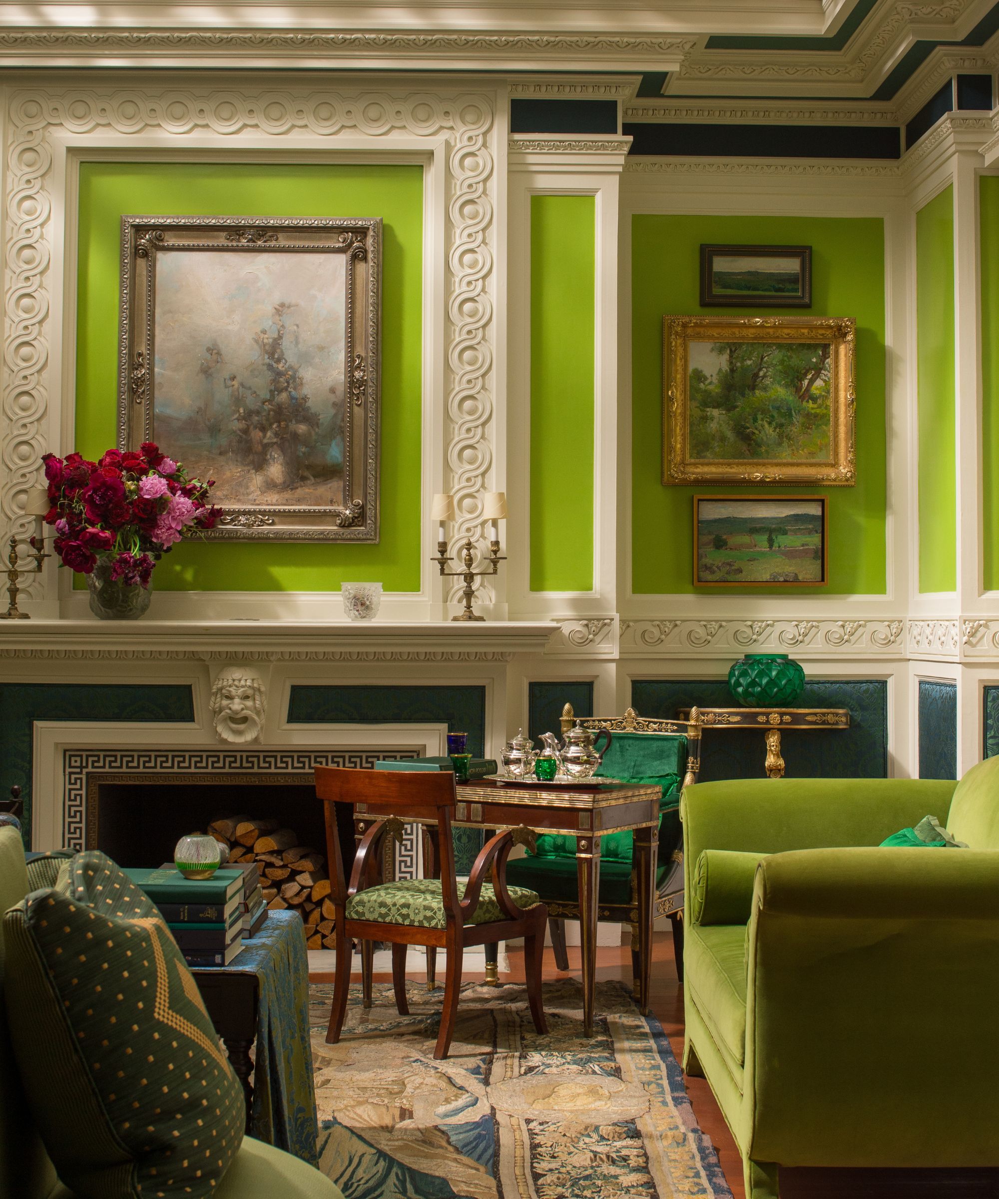 Ornate living room with crown molding, fireplace, antique art, dark wood dining chairs and table and green velvet armchair