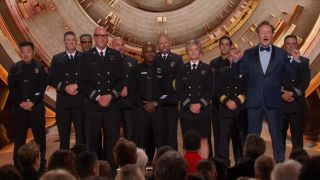 Conan O'Brien stands on stage with a bunch of Los Angeles firefighters at the 97th Academy Awards.