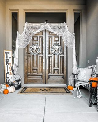 Porch with trick or treat sign, cobwebs, skeleton and pumpkins for Halloween