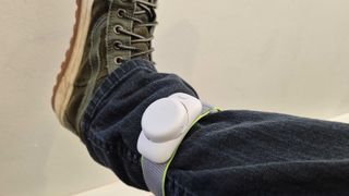 Pico 4 Ultra Motion Tracker on a person's leg, they're over the top of black jeans