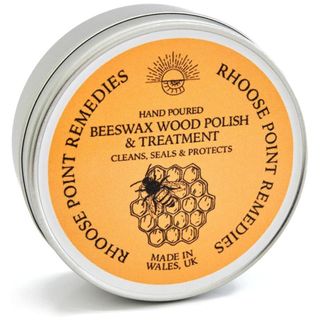 A silver circular tin of beeswax wood polish with a yellow label