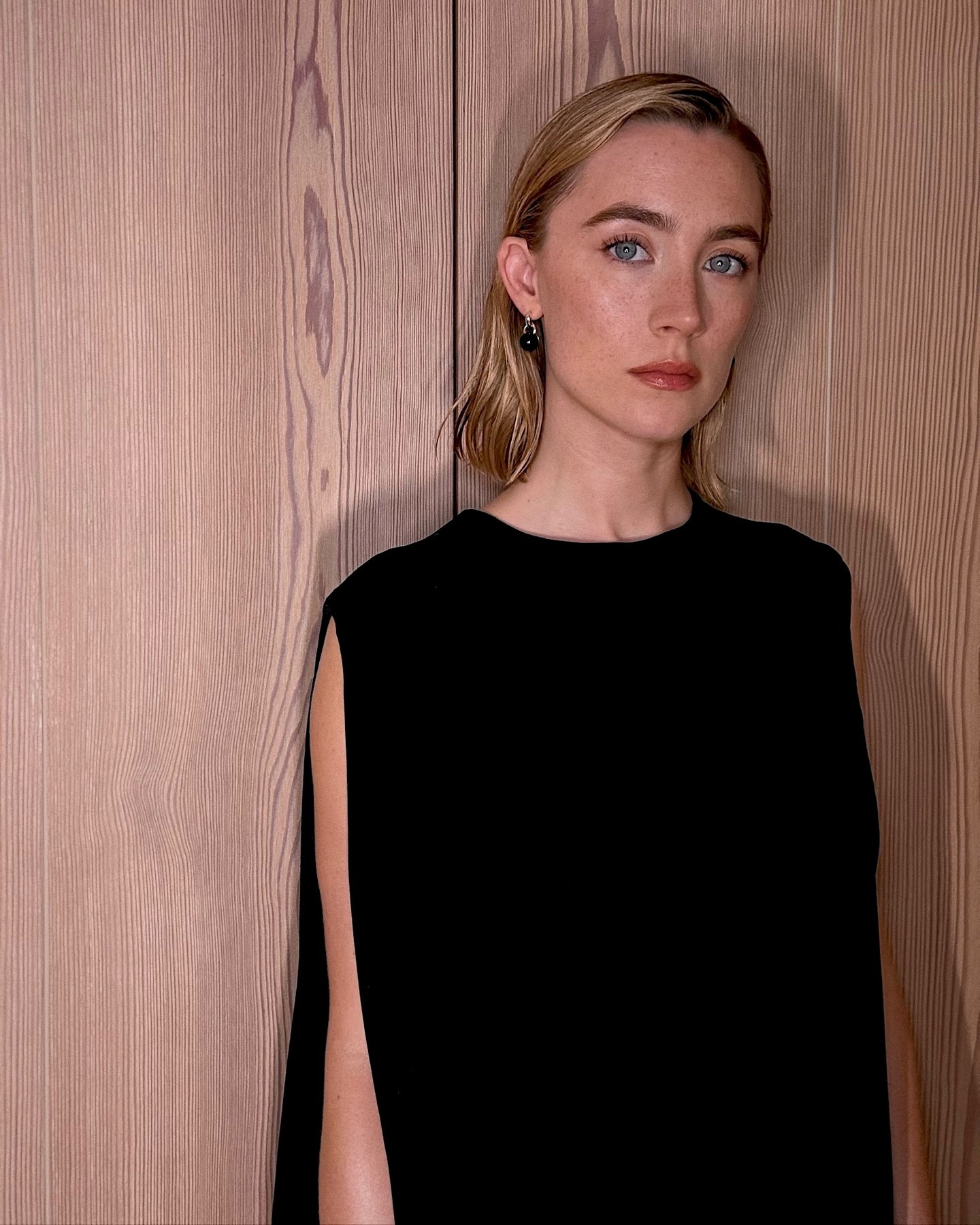Saoirse Ronan wearing a black dress with a golden blonde bob hairstyle