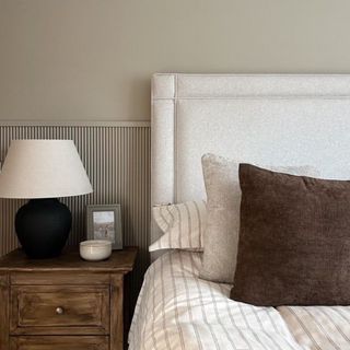 A neutral bedroom with half-height ribbed wall panelling behind the bed