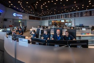 a mission control room full of people looking at computer monitors