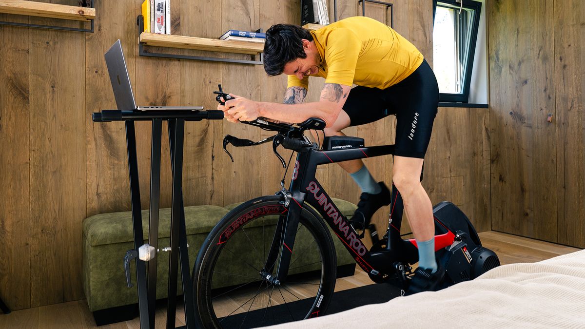 A white man riding a Quintana Roo time trial bike in an indoor session using Rouvy