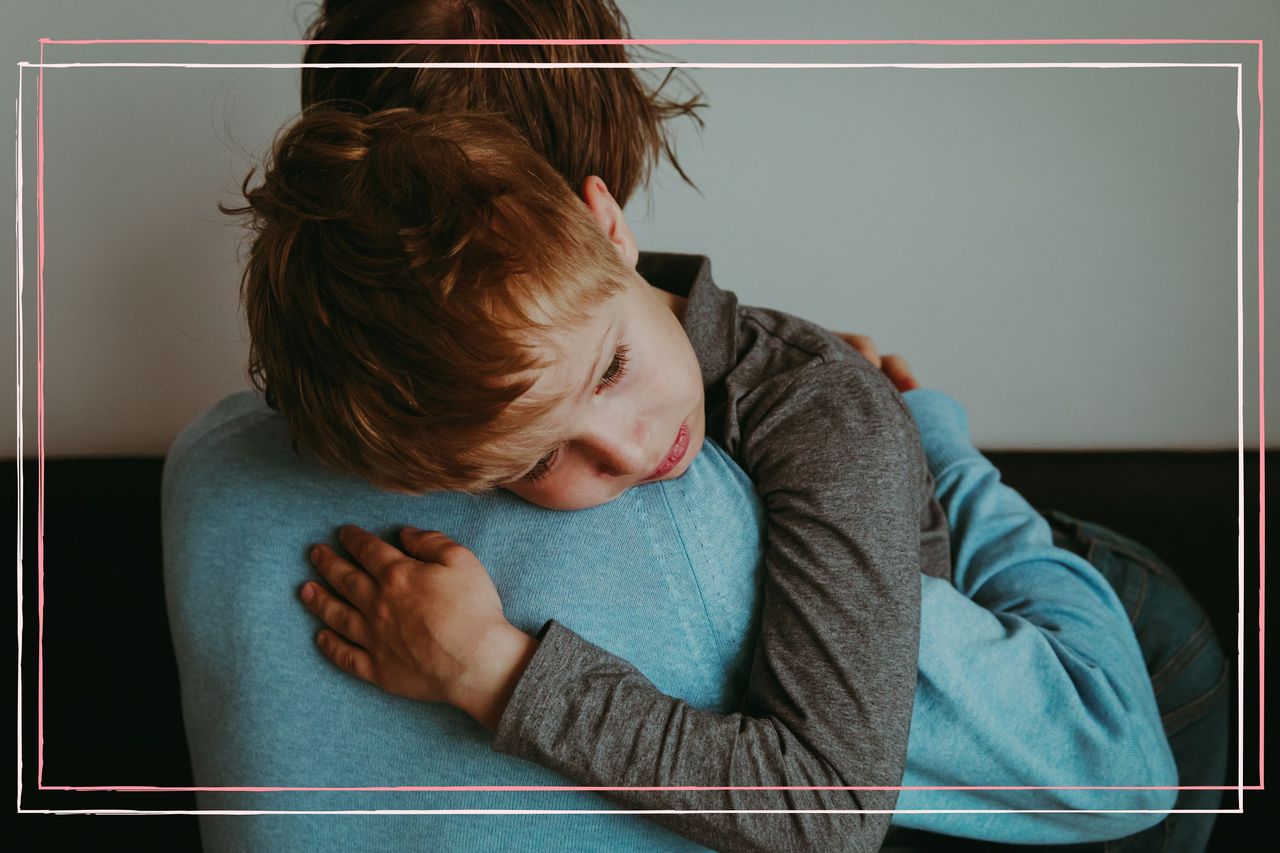 A man hugging a young boy who looks upset