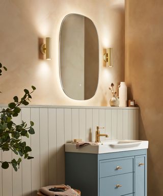 A bathroom vanity with a large mirror and two matching vertical wall sconces