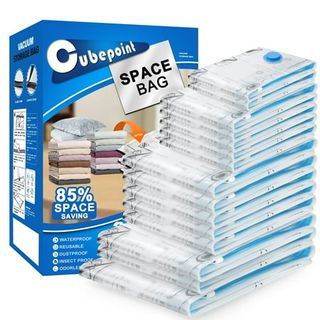 A stack of clear plastic vacuum storage bags with blue tops, folded up in a pile from small bags to large. In front of a blue cardboard box. 