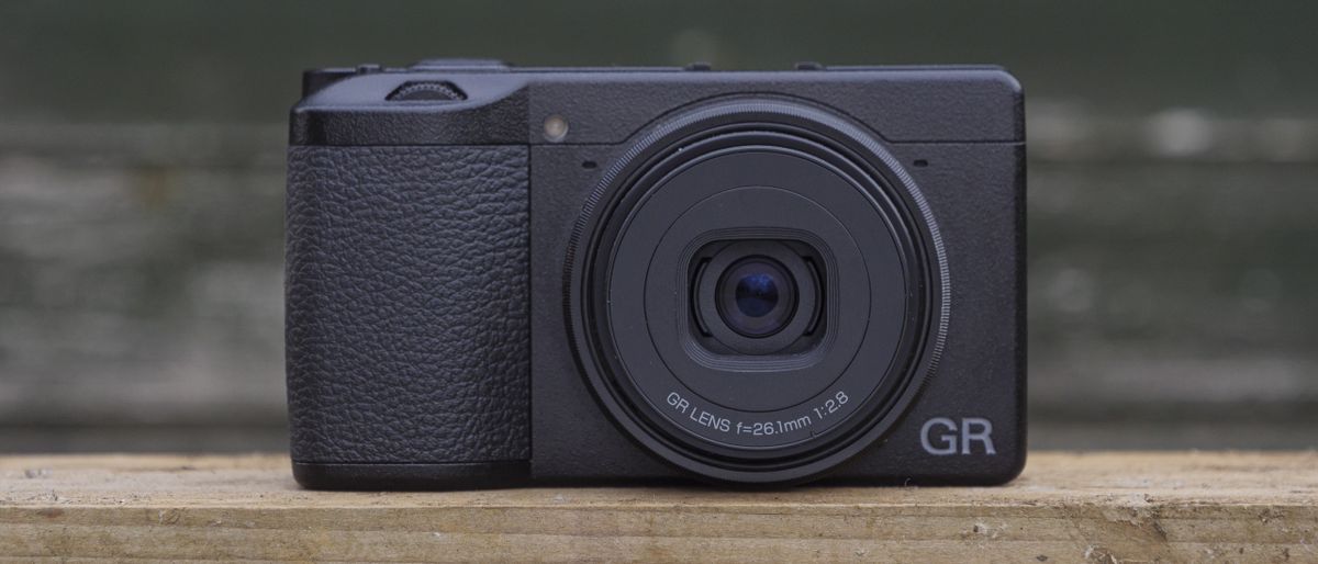 The Ricoh GR IIIx camera on a wooden table outside