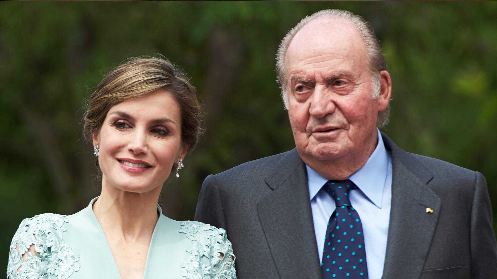 Queen Letizia wearing a mint dress smiling next to King Juan Carlos