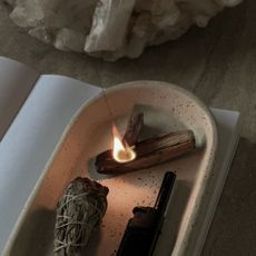 A woman meditating, practicing yoga and using sage in her home