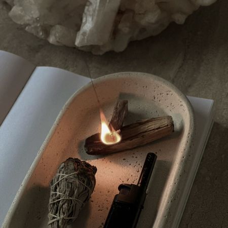 A woman meditating, practicing yoga and using sage in her home