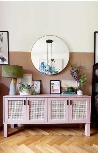 pink rattan sideboard with a velvet lamp, vase of flowers and an art print