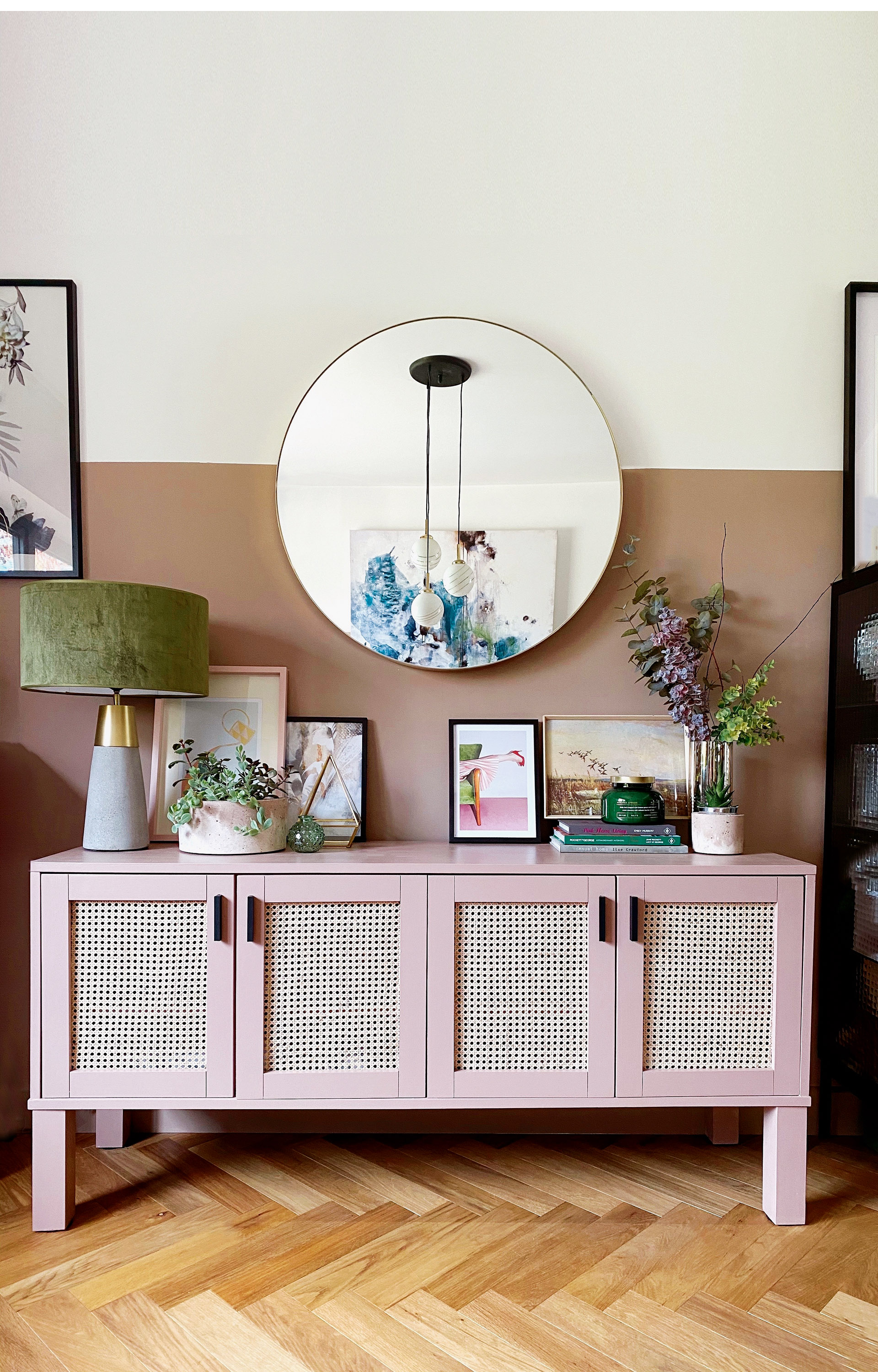 pink rattan sideboard with a velvet lamp, vase of flowers and an art print