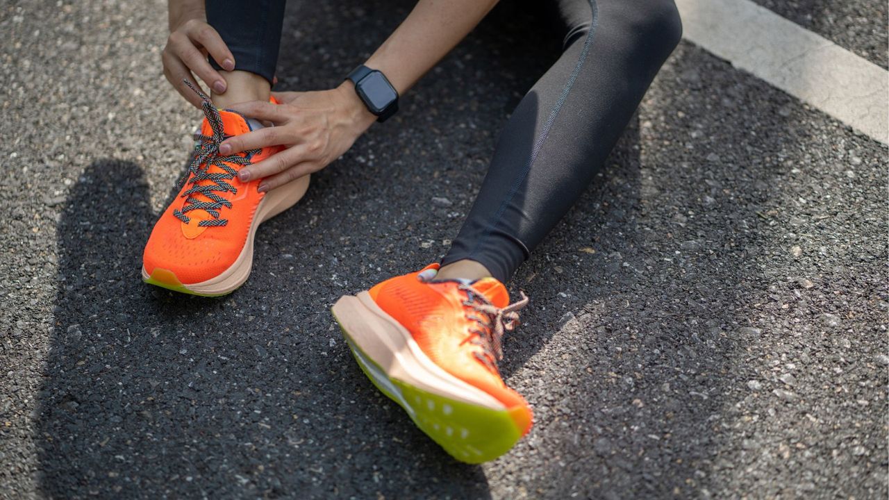 Woman tying up running shoes, sitting down on gravel after running 30 minutes a day