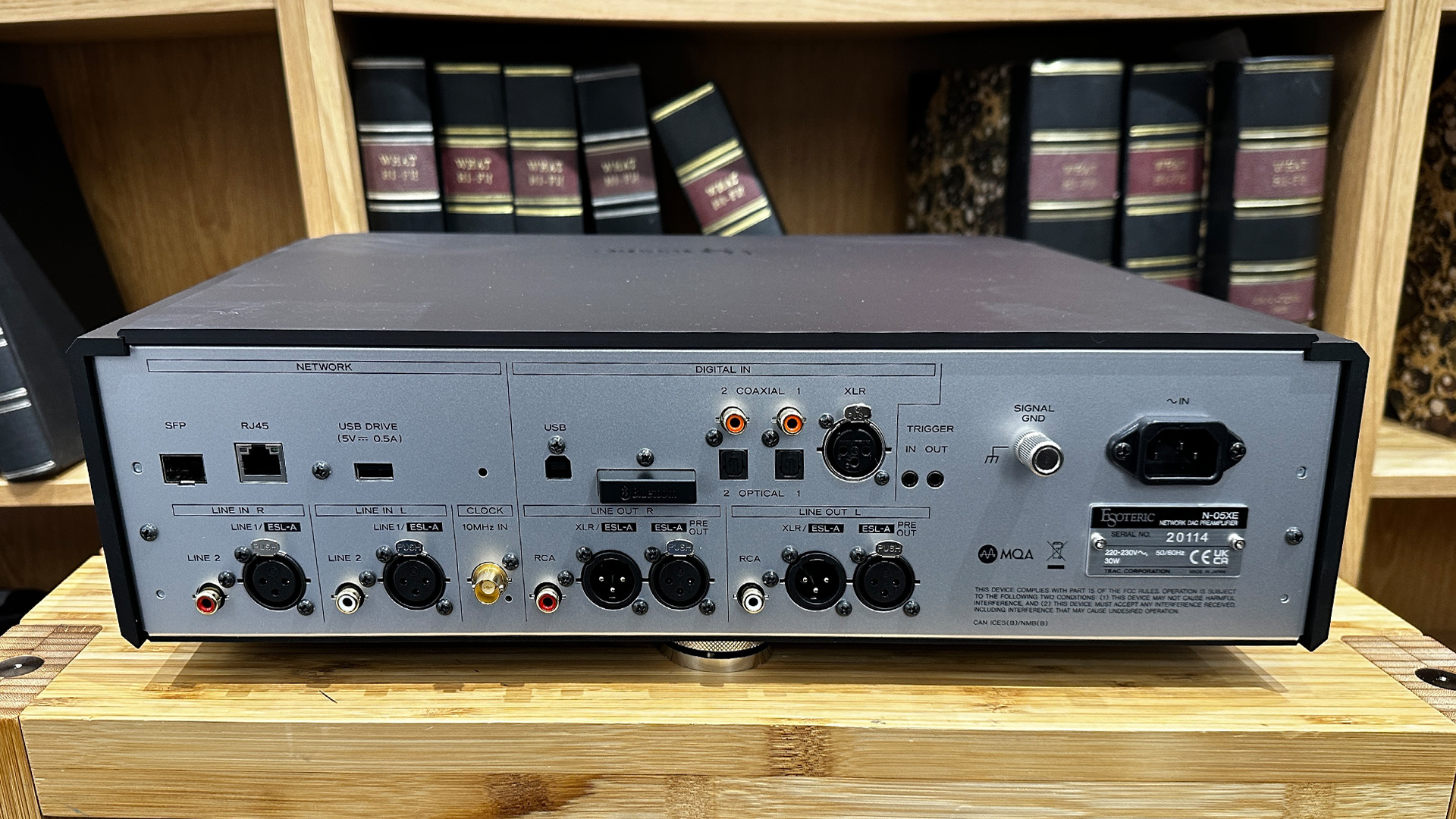 Esoteric N-05XE streaming preamp on wooden hi-fi rack in front of bookcase, rear of unit showing connections
