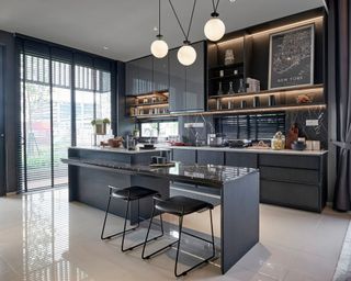 Black small kitchen with marble countertops and a three-globe pendant statement light in white with black wiring over the island
