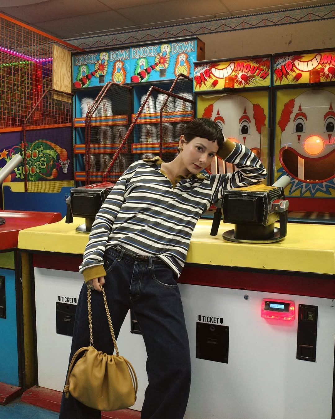 Woman wears striped jumper, blue jeans and holds beige Loewe Flamenco bag