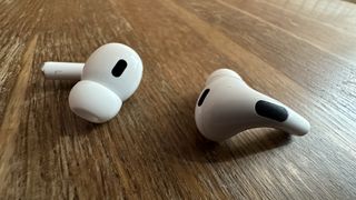 AirPods Pro 2 liggende på træoverflade