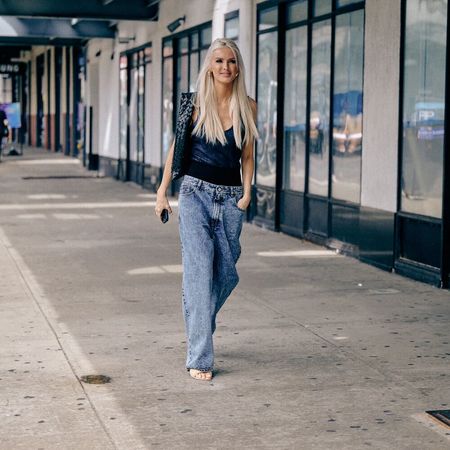 woman wearing jeans and sandals and a black tank top in nyc street style