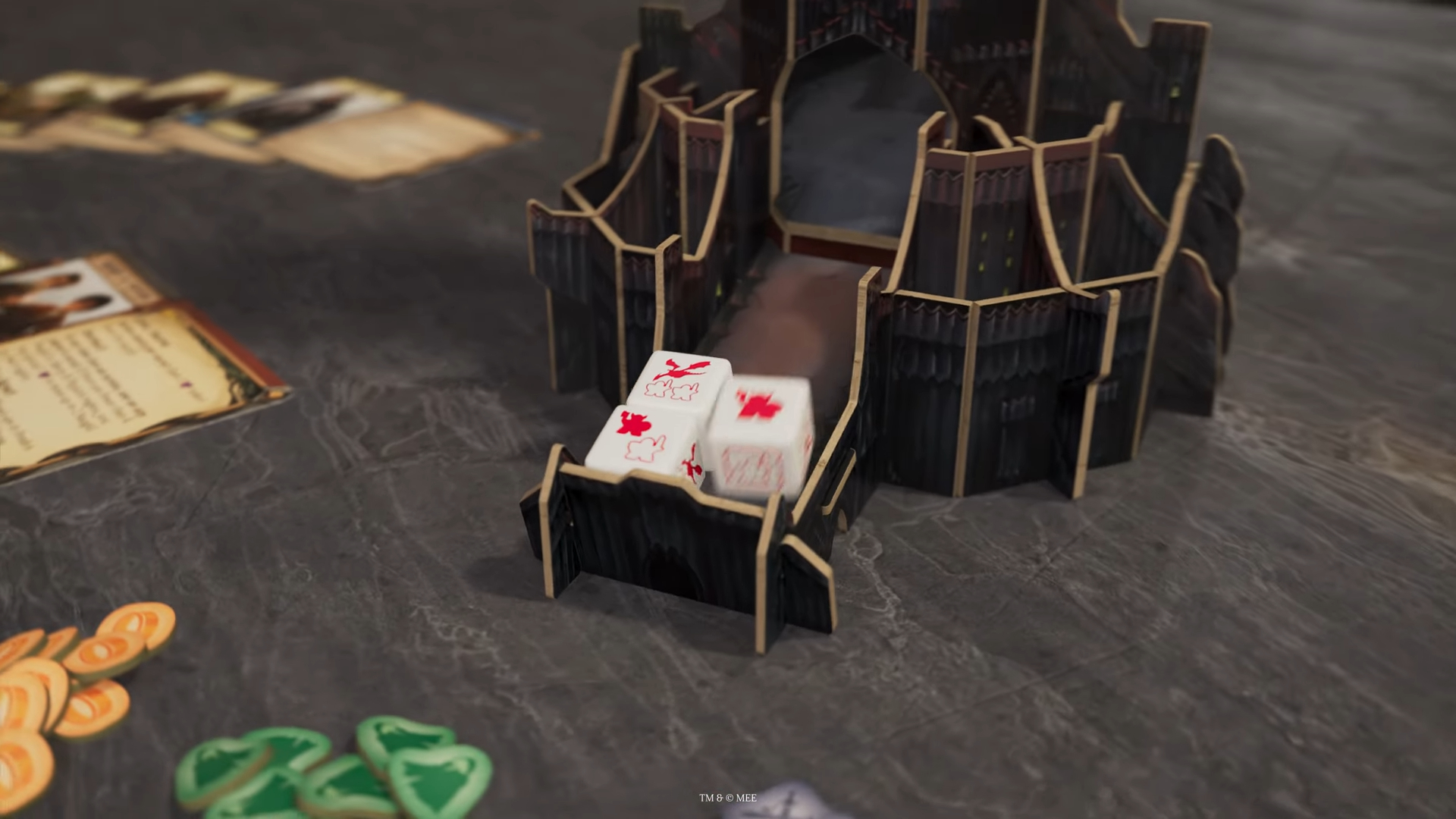Dice fall to the base of a tower shaped like Barad-dur, with cards and tokens visible nearby on a slate-gray surface