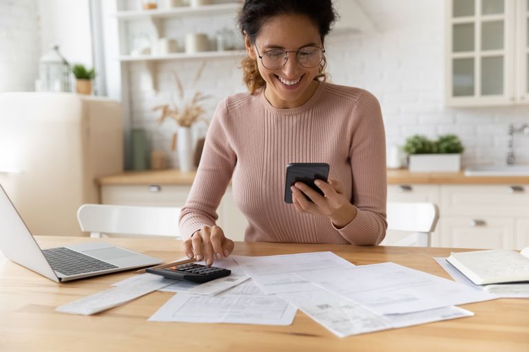 Smiling woman using a smartphone and doing paperwork