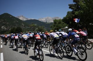 The pack of riders (peloton) cycles during the 18th stage of the 111th edition of the Tour de France cycling race, 179,5 km between Gap and Barcelonnette, in the French Alps in southeastern France, on July 18, 2024. (Photo by Anne-Christine POUJOULAT / AFP) (Photo by ANNE-CHRISTINE POUJOULAT/AFP via Getty Images)