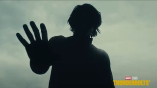 A sinister superhero stands in silhouette