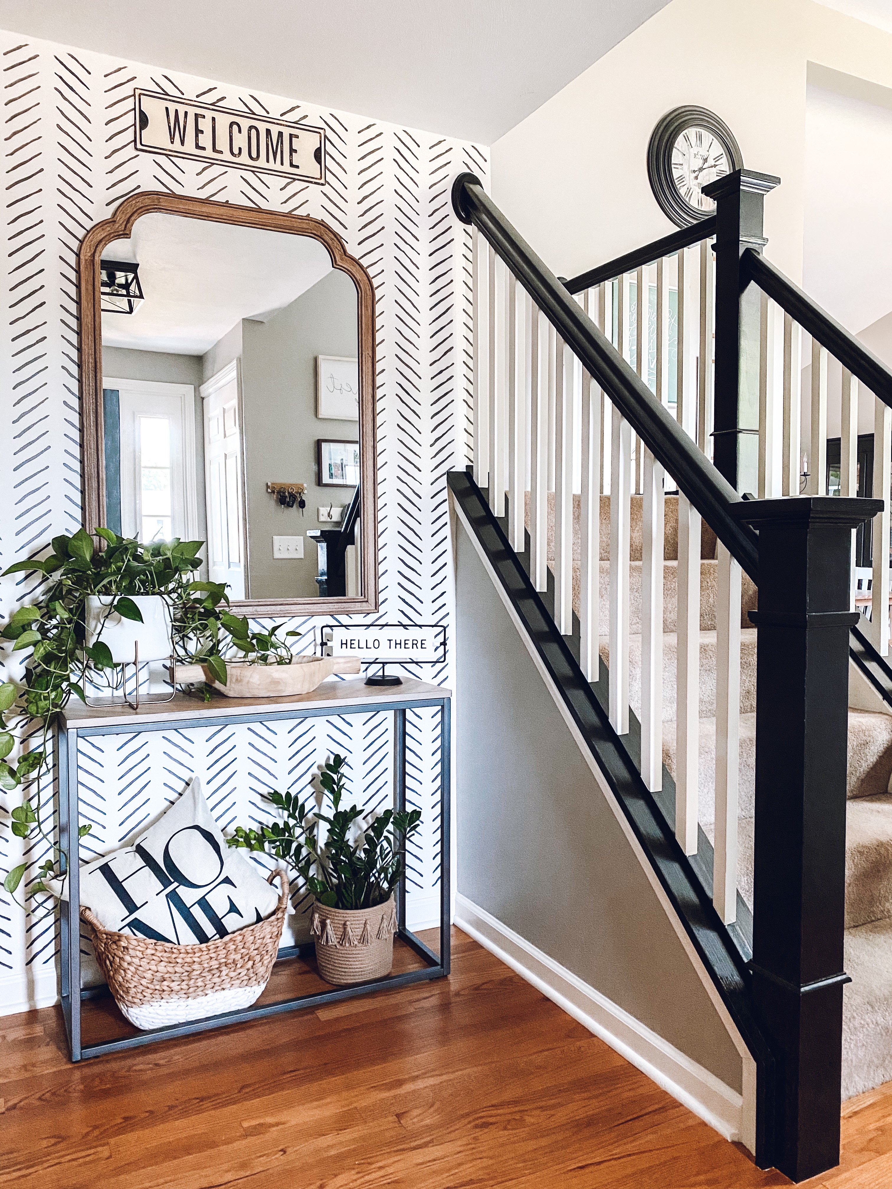 Monochrome entryway with black staircase banister and large mirror