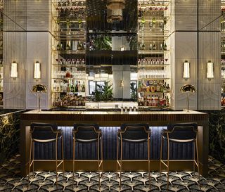 Beefbar interior cocktail bar with brass and black leather bar stools, brass lamp shades