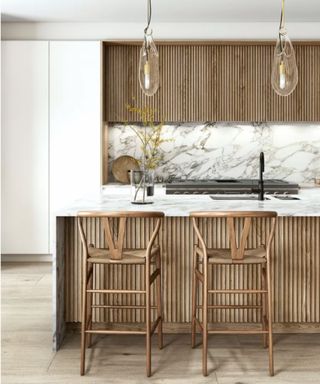 A brown woode fluted kitchen with white marble counter tops and backsplash