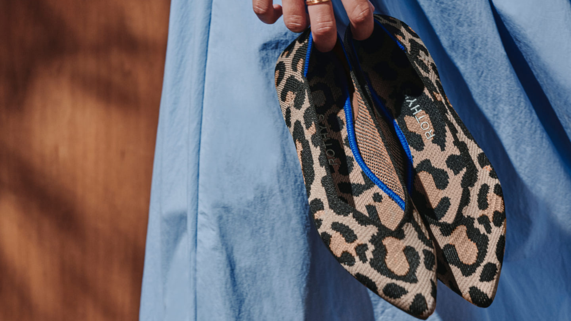 woman holding Rothy's animal print flats