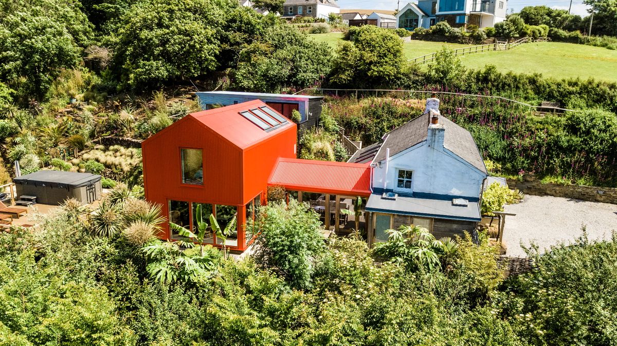 A bright orange extension on a cottage surrounded by plants