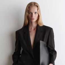 A female model wearing a dark brown blazer from COS.